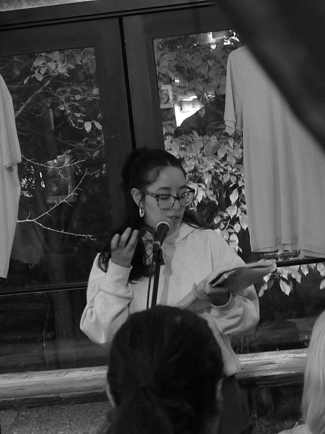 A poet reading into a microphone at an intimate community event